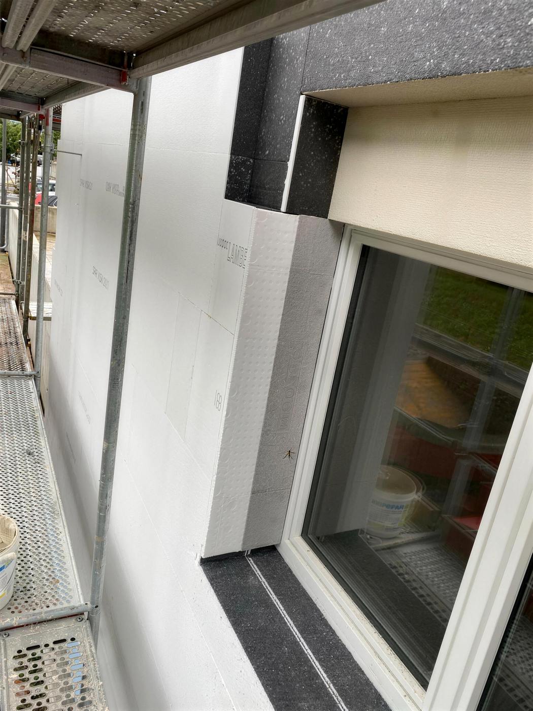 Panneaux isolants blancs posés autour d’une fenêtre, échafaudage