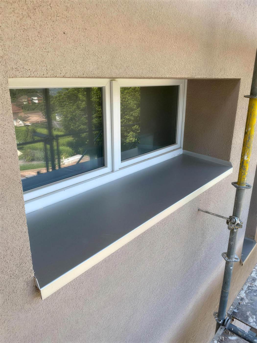 Crépi beige autour d’une fenêtre à tablette anthracite
